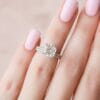 2 Ct Elongated Cushion Cut Engagement Ring Set with a hidden halo and a matching micro-pavé wedding band on a hand with pink nails.