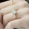 4 ct round diamond engagement ring held in fingers rose gold side view showing slim polished band and elevated claw basket