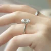 The Seraphina | Hidden Halo Oval Moissanite Engagement Ring A beautiful 14K white gold hidden halo oval moissanite engagement ring on a finger