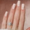 Oval Engagement Ring with Wedding Band Set A woman's hand with a light pink nail polish wearing a 2.5-carat oval cut moissanite engagement ring and a matching wedding band.