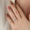 The Elara | Emerald Cut Moissanite Engagement Ring with Hidden Halo Emerald cut engagement ring with hidden halo in 14K white gold on a finger