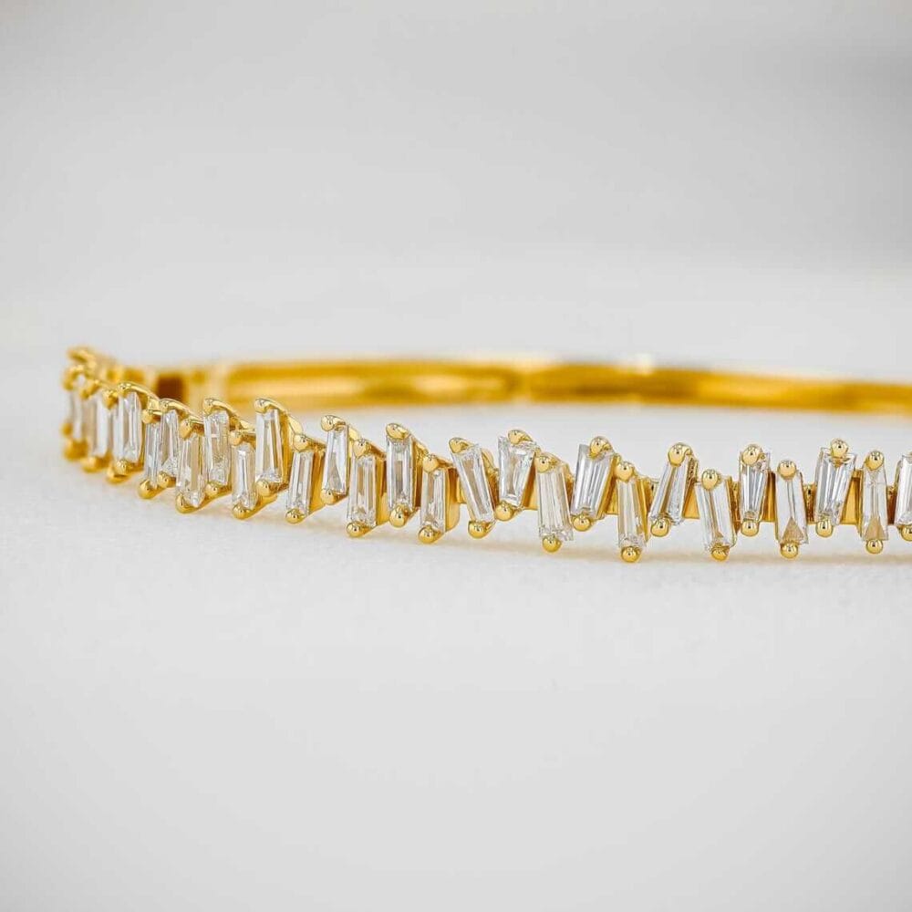 This luxurious Tapered Baguette Moissanite Bangle Bracelet, crafted in 14K gold, exudes classic elegance and refined style. Perfect for special occasions and daily